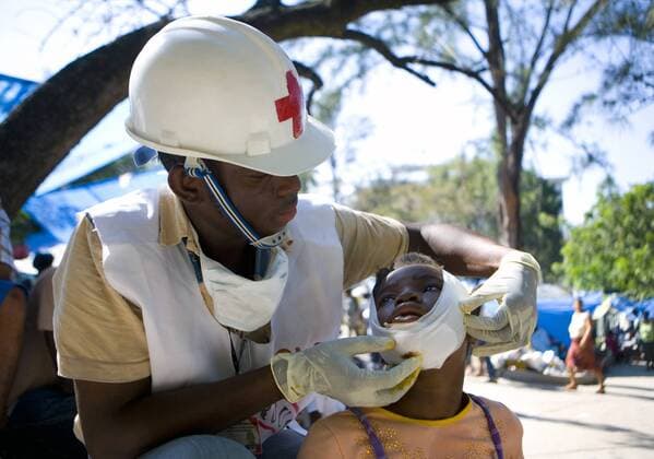Haitian Red Cross volunteer Jean Zacharie delivers first aid to a child in Port-au-Prince, Haiti on January 15, 2010. A 7.3 magnitude earthquake hit Haiti on January 12, devastating the country s capital and surrounding cities.  WAX20100116702