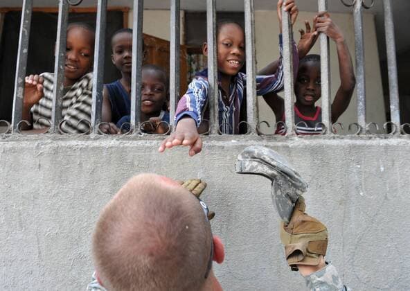 A child tries to touch the hair of Srg. 1st Class Matthew White of the Black Falcon Battalion of the 82nd Army Airborn at an orphanage in Port-au-Prince, Haiti on January 26, 2010. Haiti continues to suffer after a 7.0 magnitude earthquake devastated the country on January 12.  HAI20100128318