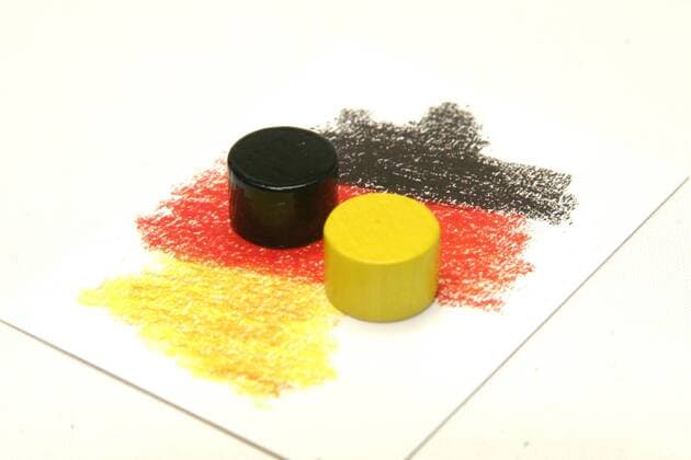 04.02.10; schwarzer und gelber Spielstein auf Spielkarten in den Bundesfarben Schwarz Rot Gold