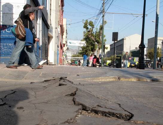 People walk by a crack in the road after an 8.8 magnitude earthquake rocked Chile, in Santiago, Chile, February 27, 2010. At least 147 people are reported dead  WAX20100227320