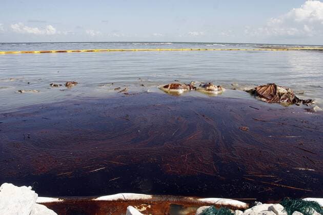 Oil collects in a cove on Elmer s Island, Louisiana. The oil washed over booms seen in the background designed to protect the beaches from crude oil gushing from the sunken BP Deepwater Horizon oil rig. Oil continues to leak from the ruptured well some 5000 feet from the surface.  NOP2010052101