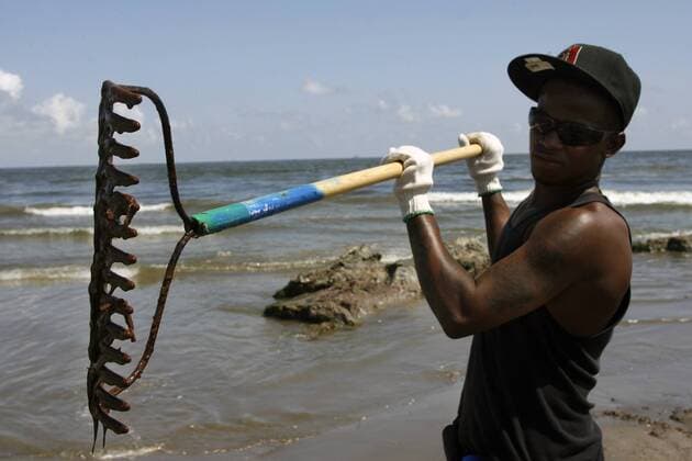 Rontrell Robertson of Houma, Louisiana, holds a rake dripping with thick crude oil scraped from the beach of Grand Isle, Louisiana, May 22, 2010. Oil has begun to wash up on South Louisiana beaches from the sunken BP Deepwater Horizon oil rig, which is gushing hundreds of thousands of gallons of crude into the Gulf of Mexico every day.  NOP2010052102