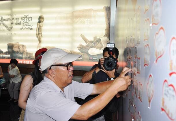 (100723) -- SUZHOU, July 23, 2010 (Xinhua) -- Zhang Hong, a 62-year-old survivor of the Tangshan quake, pastes the paper written with his good wishes on the wall during a premiere of the film Aftershock in Suzhou, east China s Jiangsu Province, July 22, 2010. In 1976, a 7.8-magnitude quake hit Tangshan City of north China s Hebei Province, and left more than 240,000 people dead. The movie Aftershock which is directed by Feng Xiaogang, reflects the devastating earthquake in Tangshan in 1976. The film, with the tagline 23 seconds, 32 years, tells the story of a mother who had to make a choice between saving her daughter or her son during the 23 seconds in which the disaster ravaged the town. Feng said the film is really a heart-touching story about family and the healing of the quake survivors emotional wounds. (Xinhua Zhu Guigen)(mcg) (1)CHINA-FILM-AFTERSHOCK (CN) 