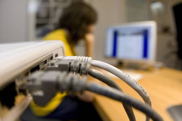  Mensch sitzt vor dem Computer, vorn ein Hub oder Netzwerkverteiler für die Internetverbindung iblbks01659723