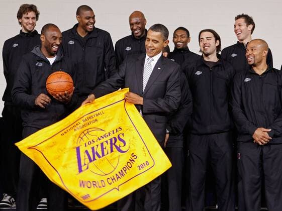 U.S. President Barack Obama (C) receives an autographed championship flag and basketball from members of the Los Angeles Lakers (L-R) Paul Gasol, Kobe Bryant, Andrew Bynum, Lamar Odom, Ron Artest, Aleksandar Vujacic, Luke Walton and Derek Fisher during an event at the Boys and Girls Club at THEARC December 13, 2010 in Washington, DC. The 2010 NBA Championship Lakers team volunteered on projects at the club before being honored by the president for their victory.  WAX2010121331