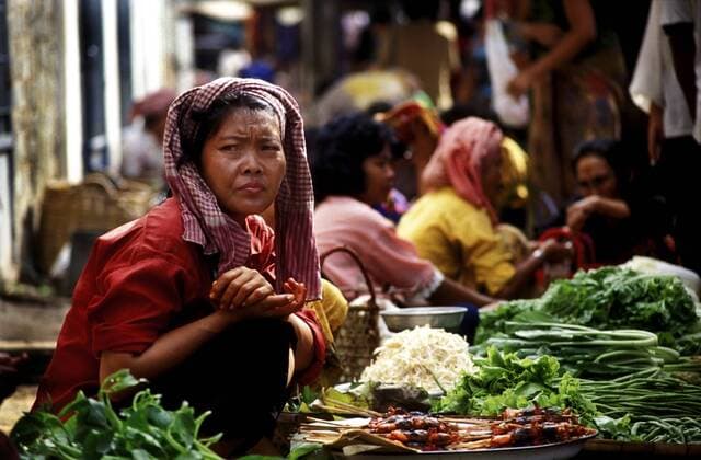 Marktverkäuferin sitzt zwischen Gemüse, Phnom Penh, Kambodscha, Asien iblklj01775961