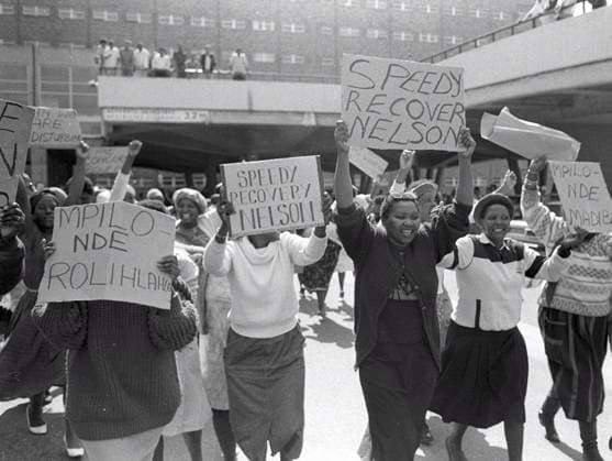 IMAGO History, Ende der Apartheid in Südafrika: 1990-1994 Mandela supporters outside hospital CAPE TOWN, SOUTH AFRICA - 1987: In 1987 political prisoner Nelson Mandela fell ill with early signs of tuberculosis and was hospitalized at Tygerberg Hospital in Cape Town. Protesters and well-wishers gathered outside to show their support for him and the apartheid struggle. ( Gallo0006860