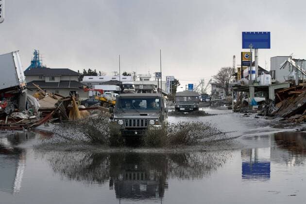 March 28, 2011, Ishonomaki, Japan - Military vehicles splash waters as they drive through the quake-devastated city of Ishinomaki, Miyagi prefecture, on Monday, March 28, 2011, as reconstruction efforts have started Ishinomaki, an industrial port some 350km northeast of Tokyo, is one of the hardest-hit areas in northeast Japan by the March 11 magnitude 9.0 earthquake and the subsequent 10-meter tsunami. Much of the town still remains submerged in muddy waters, which have hampered the efforts of people searching for missing kin and reconstruction.  (uukb001078)