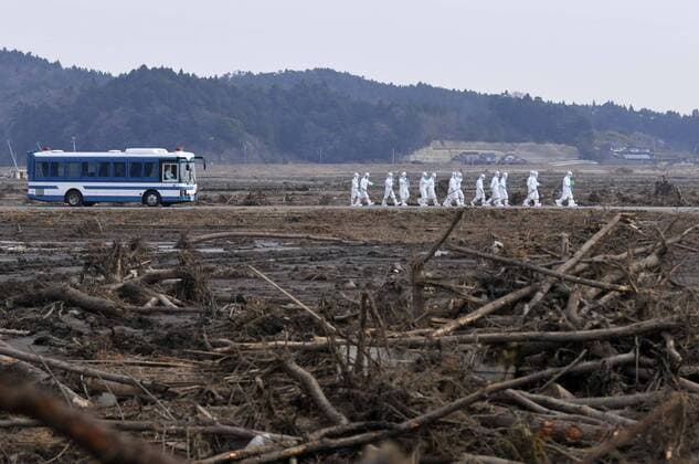 April 15, 2011, Minami - Soma, Japan - Wearing protective gear, a police search party shift through debris as they search for missing people in Minami-Soma, Fukushima Prefecture, on Friday, April 15, 2011. Southern half of the town falls within the 20km radius from the crippled Fukushima No. 1 nuclear power plant, where residents have been ordered to evacuate. More than 2,200 people have been missing in Fukushima Prefecture alone since an earthquake and tsunami hit Japan northeastern region on March 11.  ( quba002239)