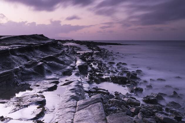 Lichtimpressionen Ost-Ende des Strands gen Westen, entlang einer der Felsbänke bei ablaufendem Wasser in der Abenddämmerung, Kilve Beach, Somerset, England, Großbritannien, Europa iblava01915067
