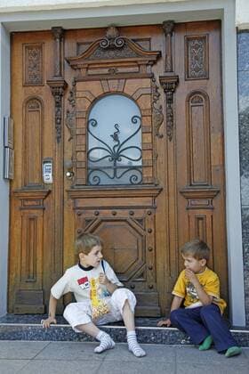 zwei Jungen sitzen vor einer Haustuer und essen Popcorn two boys sitting in front of entry door and eating popcorn BLWS256592
