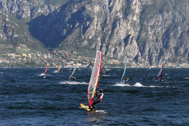 Windsurfer surfen bei starkem Wind auf dem Gardasee bei Malcesine, dahinter Limone, Venetien, Italien, Europa iblebo01957805
