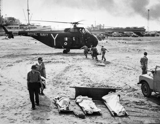 Port Said , Egypt : Stretcher bearers hurry with a wounded man to a Royal Navy helicopter at Port Said to take the injured to British ships at sea for treatment . In the foreground are wounded Egyptians who have been brought back by the helicopter after being treated aboard the British ships . 8 November 1956 Mono Negative !AUFNAHMEDATUM GESCHÄTZT! UnitedArchives1221604