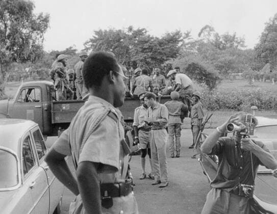 Leopoldville , Congo : Watched in turn by camera crews and newsmen , Congo strong man Colonel Joseph Mobutu looks on as Patrice Lumumba , the ex Prime Minister of the Congo , is taken away by his soldiers here on December 3nd . 5 December 1960 Mono Book Illustration !AUFNAHMEDATUM GESCHÄTZT! UnitedArchives1239714