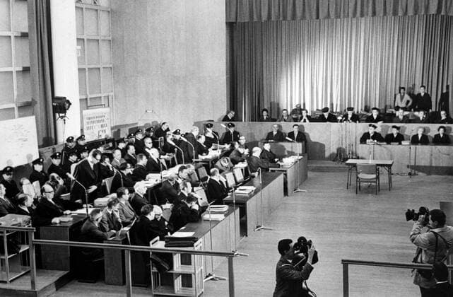 Eight of the 22 defendants in the Auschwitz trial sit between defence counsels and police during the 32nd session of the marathon war crimes trial . 7 April 1963 Mono Negative !AUFNAHMEDATUM GESCHÄTZT! UnitedArchives1272999