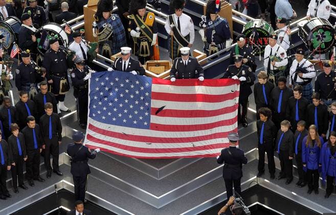 20 Jahre Anschläge vom 11. September: Gedenkkultur in den USA A Flag from the site of the World Trade Center is held on the stage as people wait to visit the Memorial Pools on the tenth anniversary of the terrorist attacks on the World Trade Center on 9 11 at Ground Zero in New York City on September 11, 2011.  NYP20110911107