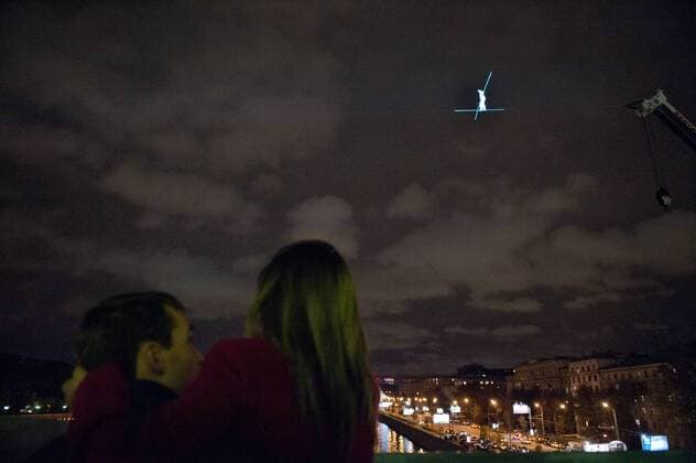 ITAR-TASS: MOSCOW, RUSSIA. SEPTEMBER 29, 2011. A young couple watch Swiss tightrope artist Freddy Nock balance at a height of 30 metres during his unsuccessful attempt to walk across a tightrope over the Moskva River. Nock performed his stunt in central Moscow, near Gorky Park, on the eve of the 5th World Festival of Circus Art.  RE0EF299