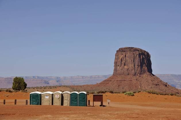 Toilettenhäuschen am Campingplatz, dahinter Gray Whiskers Butte, Monument Valley, Navajo Tribal Park, Navajo Nation Reservation, Arizona, Utah, Vereinigte Staaten von Amerika, USA iblwmi02049410