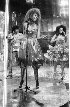 Pointer Sisters (Gesangsgruppe) 05 85 haef Die Pointer Sisters im Mai 1985 in Na Sowas (ZDF) von links: Ruth, Anita (vorne) und June Pointer Frau Frauen Gesangsgruppe Gruppe Popgruppe 40er Jahre-Jazz Dixieland Big Band Funk R&B Country Gesang Musikerinnen Musik Sängerin Sängerinnen Amerika Amerikanerinnen dunkelhäutig dunkelhaarig langhaarig Locken gelockt Kleid Kleider gestikulierend Gestik Mikro Mikros Mikrofone Veranstaltung Auftritt Studio Fernsehstudio Kulisse live singend hoch Hochformat ganz stehend sw schwarzweiß