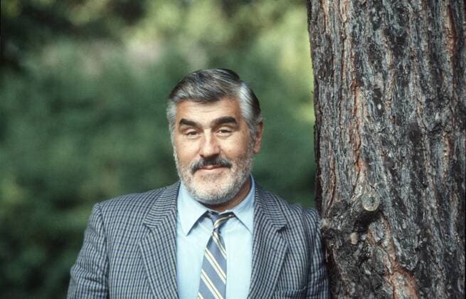 Mario Adorf (Schauspieler) 05 87 scha Mann Schauspiel Schauspieler Film Fernsehen TV Theater grauhaarig kurzhaarig Schnäuzer Bart Vollbart halb quer stehend seriös Jackett Krawatte lächelnd Baum angelehnt