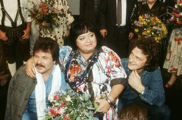 Trude Herr mit Thommy Engel (li., De Bläck Fööss ) und Wolfgang Niedecken ( BAP ) 01 88 - Schauspielerin Schauspiel TV Fernsehen Gesang Musik Ich will keine Schokolade dunkelhaarig kurzhaarig leger kniend hockend halb quer lächelnd sich umschauend angelehnt Blumen Blumenstrauss