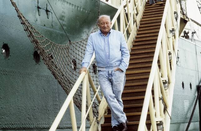 James Krüss 04 88 hör Mann Autor Schriftstellerei grauhaarig Halbglatze leger Jacke Hemd blau Jeans quer ganz stehend draußen Treppe Schiff neutral