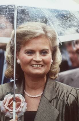 Hannelore Kohl (Ehefrau des Bundeskanzlers) 07 88 hör Frau Ehefrau des Bundeskanzlers Gesellschaft Politik dunkelhaarig blondiert blond kurzhaarig Locken Schmuck Ohrring Kette seriös Jacke gold-schwarz glänzend Top schwarz Rose als Anstecker Anstecknadel Brosche Blüte stehend draussen Portrait hoch lächelnd Schirm Regenschirm Regen