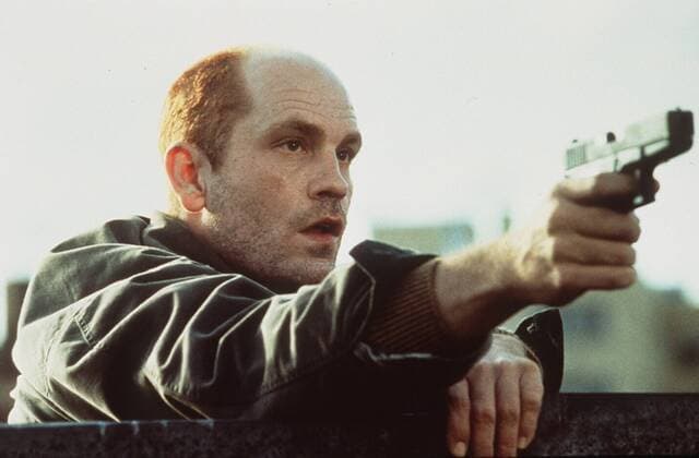 In the Line of Fire mit John Malkovich 10 93 teu Film Kino USA Mann dunkelhaarig leger Jacke Waffe Pistole haltend bedrohend ernst Szene Filmszene halb quer draußen