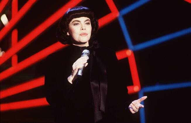 Mireille Mathieu (Sängerin) 01 88 dar Frau Gesang Musik Schlager dunkelhaarig Pagenkopf Frankreich festlich Kleid schwarz Schleife Auftritt Bühne Show Studio Kulisse Dekoration Mikrophon haltend halb quer singend gestikulierend