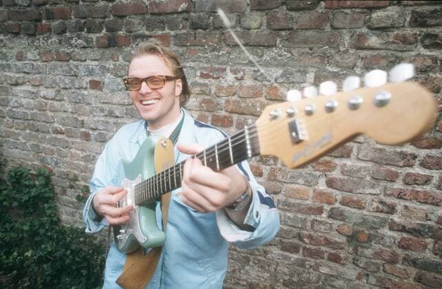 Stefan Raab 02 96 mo Mann TV Moderation Musik VIVA Unterhaltung dunkelhaarig Brille leger Jacke blau quer halb stehend Instrument Gitarre spielend draußen lächelnd