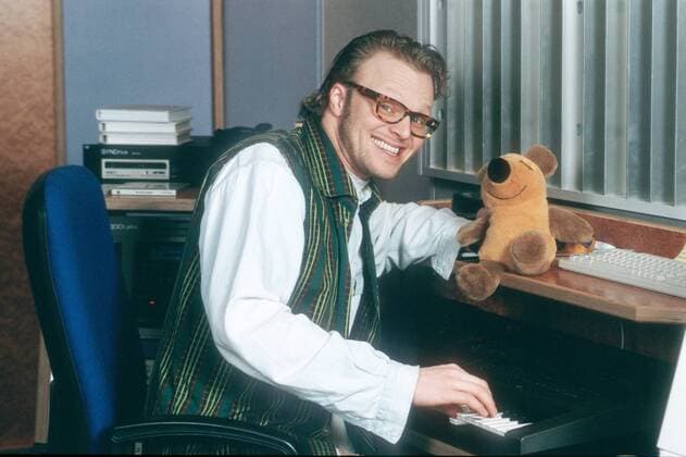 Stefan Raab 02 96 mo Mann TV Moderation Musik VIVA Unterhaltung dunkelhaarig Brille leger Hemd Weste quer halb sitzend Stuhl Instrument Keyboard spielend Stofftier Maus lächelnd