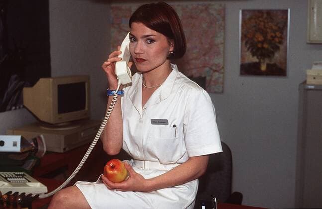 Claudia Schmutzler in Für alle Fälle Stefanie (SAT.1) 06 96 te Schauspiel TV Fernsehen Serie Frau dunkelhaarig Verkleidung Kittel weiß Krankenhaus sitzend Regal Buch Tisch telefonierend Frucht Apfel haltend quer halb neutral