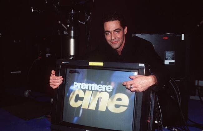 Christian Clerici in cine magazin (Premiere) 12 96 her Mann TV Fernsehen Moderation Kino Film dunkelhaarig leger Hemd Jackett schwarz Monitor Logo stehend haltend Kamera Logo halb quer lächelnd