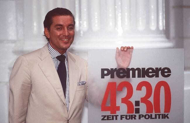Michel Friedman in 43:30 - Zeit für Politik (Premiere) 07 97 her Mann Politik Zentralrat der Juden Justiz Judentum CDU TV Fernsehen Moderation dunkelhaarig seriös Hemd kariert Krawatte Jackett stehend Schild Logo Studio Kulisse Dekoration haltend halb quer lächelnd