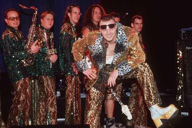 Stefan Raab und Band 11 97 her Mann TV Moderation Musik VIVA Unterhaltung dunkelhaarig Sonnenbrille leger Plateauschuh Leopardenhose quer ganz stehend Instrument neutral Bühne
