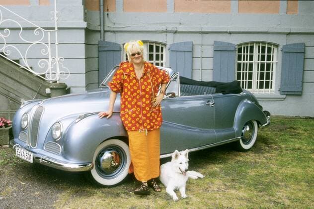Gaby Köster und Hündin Frau Doktor mit BMW V 8 in auto motor und sport tv (VOX) 06 97 böw Frau TV Fernsehen Kabarett ENTERTAINMENT Komik blond langhaarig Hochsteckfrisur leger Bluse Rock orange draußen Auto Tier Haustier Hund stehend angelehnt Haus Gebäude Treppe ganz quer Sonnenbrille lächelnd Cabriolet Bj. 1955