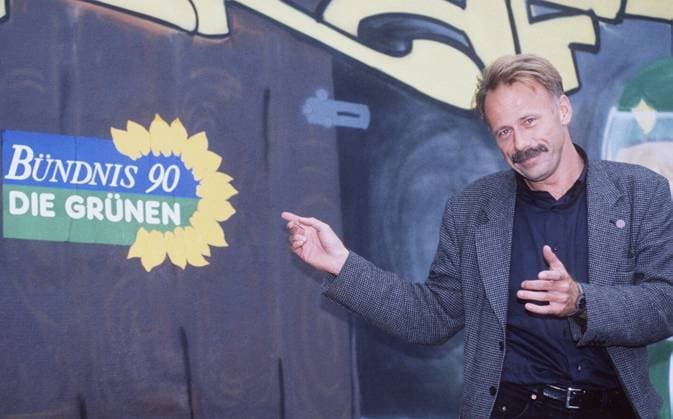 Jürgen Trittin ( Die Grünen -Politiker) 08 98 af Mann Politik kurzhaarig Schnäuzer leger stehend Podium Mikrophon stehend draußen Plakat Schild Die Grünen halb quer sprechend gestikulierend