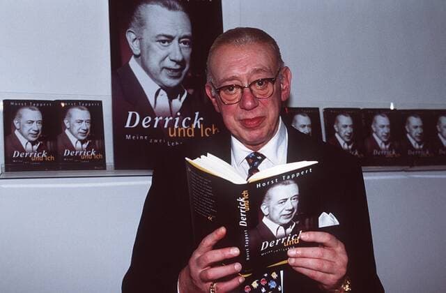 Horst Tappert (Schauspieler) 10 98 am Mann TV Fernsehen Schauspiel Theater Serie grauhaarig Brille seriös Hemd Jackett Krawatte stehend Autor Buch Literatur Schriftstellerei Plakat stehend haltend Derrick halb quer neutral
