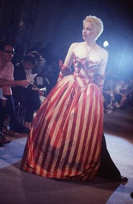 Modenschau der Modeklasse von Vivienne Westwood 07 99 urb Frau Großbritannien Punk Mode Design Modemacher England Modenschau Model Menschen Zuschauer Laufsteg Saal Lampe Handschuhe lang ganz hoch Scheinwerfer sexy Kleid gestreift Dekollete halbnackt Brustwarze Tätowierung Garderobe Kleidung