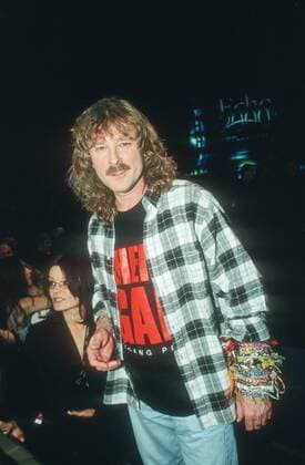 Wolfgang Petry (Sänger) 03 00 urb Mann Musik Gesang Schlager dunkelhaarig langhaarig Locken Schnäuzer leger Hemd kariert T-Shirt schwarz mit Aufdruck Aufschrift Armbänder Bänder um das Handgelenk stehend Saal Halle dunkel halb hoch lächelnd Echo 2000 am 09.03.2000 in Hamburg