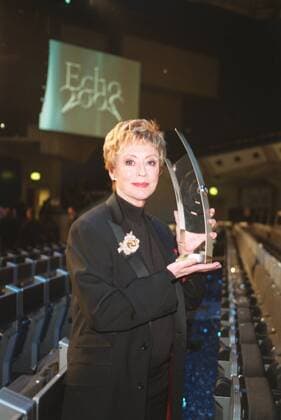 Caterina Valente (Sängerin, Schauspielerin), Preisträgerin Echo 2002 mit ihrem Preis 03 02 urb Frau Gesang Musik Show Kabarett Tanz Unterhaltung Entertainment Entertainerin Schauspiel rothaarig kurzhaarig Schmuck Anstecknadel Brosche seriös festlich Blazer schwarz Pullover Rollkragen stehend Saal Halle zwischen Stuhlreihen Preis haltend hochhaltend zeigend präsentierend im Hintergrund Leinwand mit Logo Auszeichnung für ihr Lebenswerk Verleihung Echo 2002 am 07.03.2002 in Berlin