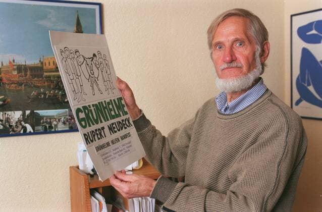 Rupert Neudeck (Journalist, Arzt) 11 03 pp Mann Journalismus Medizin Mediziner Arzt Doktor Autor Schriftsteller Literatur Gründer des Komitees Komitee Cap Anamur Afghanistan Gesellschaft Grünhelme e.V. Buch grauhaarig kurzhaarig Bart leger Hemd Pullover halb quer nachdenklich Plakat haltend Fototermin Homestory in Troisdorf Ortsteil Spich (exklusiv)
