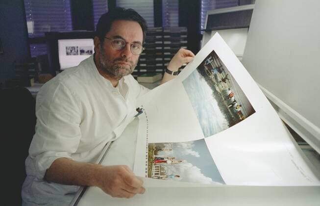 Gerhard Steidl (Verleger) 12 04 thg Mann Medien Verlag Verleger Autor Literatur Schriftstellerei kurzhaarig dunkelhaarig Brille Bart leger Hemd halb quer sitzend lächelnd Büro Plakat Bogen Papierbogen Druckfahne Papierfahne Leuchttisch haltend aufgestützt Fototermin am 20.12.2004 in Göttingen (exklusiv)