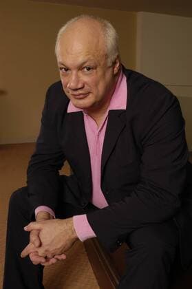 Eric Emmanuel Schmitt (Schriftsteller) 03 05 pp Mann Frankreich Literatur Autor Schriftsteller Monsieur Ibrahim und die Blumen des Koran grauhaarig kurzhaarig leger Jackett Hemd halb hoch lächelnd sitzend aufgestützt Hände gefaltet lit.Cologne am 17.03.2005 in Köln