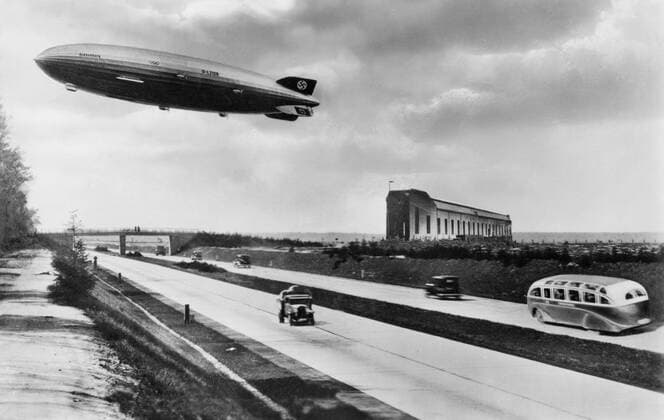 Luftschiff Hindenburg 05 10 teu Zeppelin LZ 129 Hindenburg ca. 1936 über dem Flug- und Luftschiffhafen Rhein-Main an der Reichsautobahn Frankfurt Main Deutschland deutsch historisch historisches Zeppeline Luftfahrt Luftschifffahrt Nazizeit Hakenkreuz Drittes Reich olympische Ringe Olympia Nationalsozialismus Olympia Olympiade Stadion Feature Symbol Autobahn Straße germany historical picture airship quer draußen fahrend schwebend fliegend sw