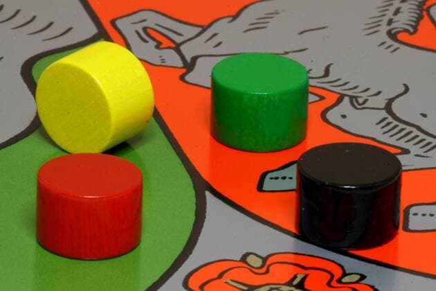 Spielsteine in den Farben der großen Volksparteien schwarz, gelb, grün und rot liegen auf dem Landeswappen von Nordrhein Westfalen