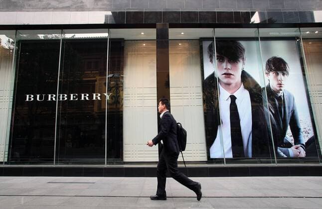--File--A pedestrian walks past a Burberry boutique in Shanghai, China, 6 April 2012. Burberry has been awarded ¡ê63 million ($100 million) in damages after taking a network of Chinese counterfeiters to court. WWD report that the defendants, who ran websites such as yesburberryvision.com and buyburberry.com, were known to have sold at least 22 different product types all bearing imitations of the British heritage brands various trademarks, such as its iconic plaid check and equestrian knight logo. The resolution of the case, which was originally filed in January at Manhattan Federal Court, comes after months of waiting for the defendants to reply to the accusations and appear in court - neither of which was ever done. The domain names for all the infringing sites will now be transferred to Burberry, allowing the brand to cut off any associated internet providers, web designers, sponso  20120406_27120