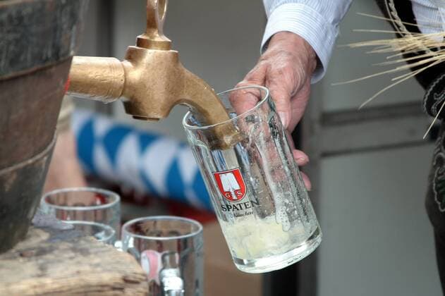 Wirt beim Bierzapfen aus einem Fass Bier auf dem Viktualienmarkt in München