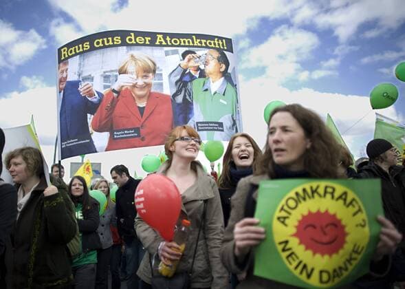 Demonstration fuer den Atomausstieg DEU, Deutschland, Germany, Berlin, 26.03.2011 Demonstrant mit Plakat Raus aus der Atomkraft mit Foto Grossmann Merkel und Ishihara bei der Demonstration mit ca 90.000 Menschen fuer den Atomausstieg unter dem Motto Fukushima mahnt alle AKWS Abschalten fuer einen sofortigen Ausstieg aus der Atomenergie in Berlin. Die bundesweiten Demonstrationen thematisieren die Auswirkungen der Naturkatastrophe in Japan und das Desaster der japanischen Atomkraftwerke. Kundgebung gegen die Atompolitik der schwarz-gelben Koalition und der Bundesregierung. Atomkraft Nein Danke, Atomkraftgegner, Antiatombewegung, Anti-Atom-Demo, Antiatom, Anti-Atomkraft, Atomkraft, Atomkraftwerke, Anti-Atom, Anti-Atom-Bewegung, Atomenergie, Atompolitik, Anti, Atomenergie, Demonstration, demonstrieren, Demonstrant, Demonstranten, Atomkraftgegener, Kernkraft, Kernkraftwerk, Kernkraftwerke, K