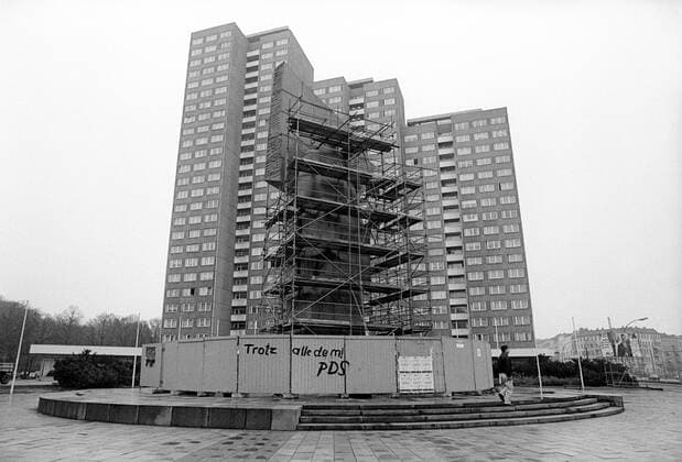 Eingezäuntes Lenindenkmal am Leninplatz in Berlin Friedrichshain - darauf ein Graffiti mit dem Schriftzug Trotz alle dem PDS